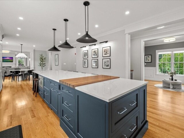 10 Beech St, Millis, MA 02054 - kitchen with light wood-style flooring, a large island, light countertops, ornamental molding, and decorative light fixtures