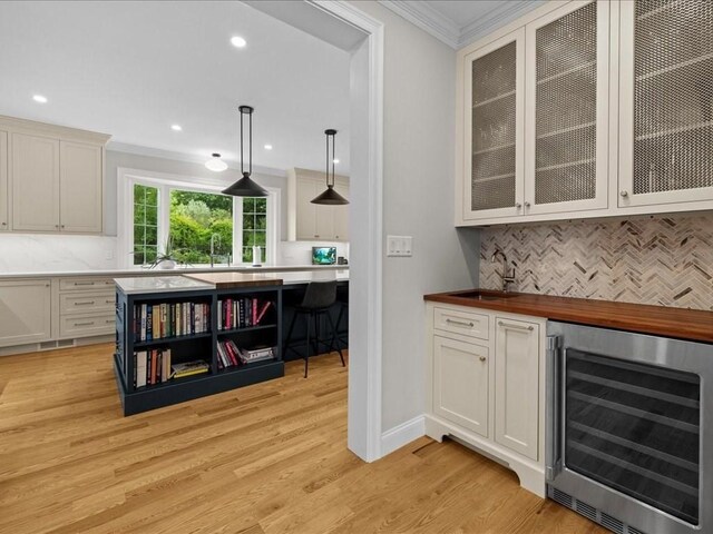 10 Beech St, Millis, MA 02054 - indoor dry bar featuring beverage cooler, ornamental molding, backsplash, light wood finished floors, and decorative light fixtures
