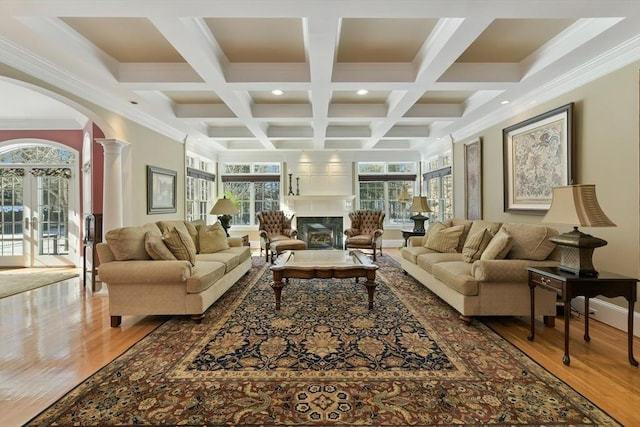 living room featuring arched walkways, a fireplace, wood finished floors, beamed ceiling, and decorative columns