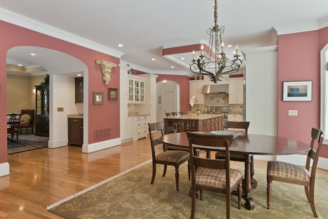 dining space with arched walkways, recessed lighting, visible vents, light wood-style floors, and crown molding