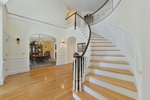 stairs featuring arched walkways, wood finished floors, and a decorative wall