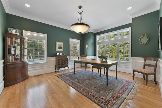 office area with light wood-style floors, ornamental molding, and a wainscoted wall