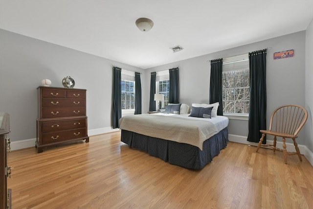 bedroom with light wood-style floors, visible vents, and baseboards