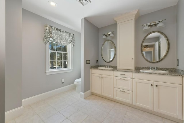 bathroom featuring toilet, visible vents, a sink, and baseboards