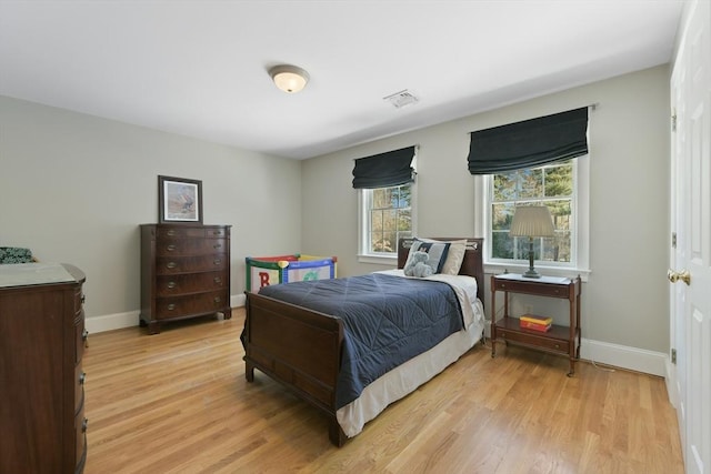 bedroom featuring baseboards, visible vents, and light wood finished floors