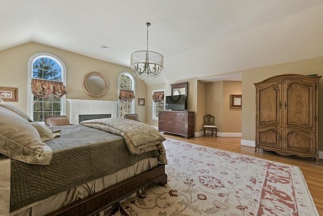 bedroom featuring lofted ceiling, visible vents, an inviting chandelier, light wood-style floors, and baseboards