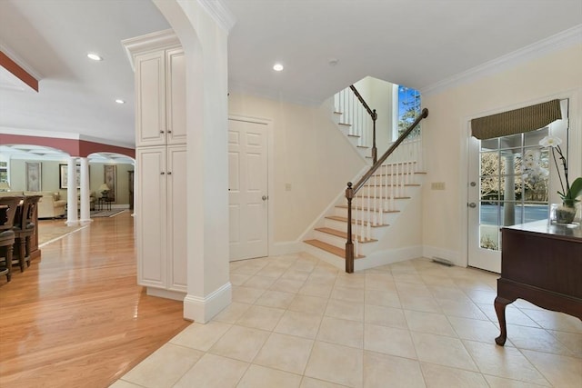 entryway featuring arched walkways, recessed lighting, ornamental molding, baseboards, and stairs