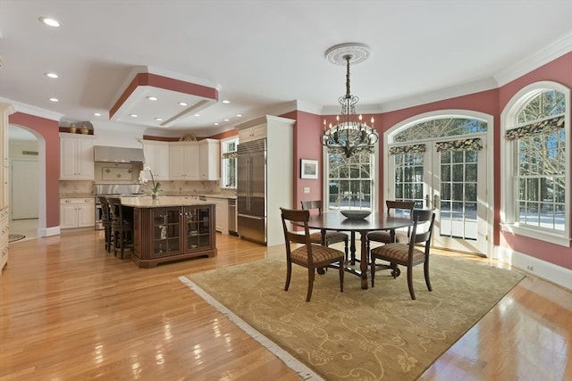 dining area featuring arched walkways, crown molding, recessed lighting, a chandelier, and light wood-type flooring