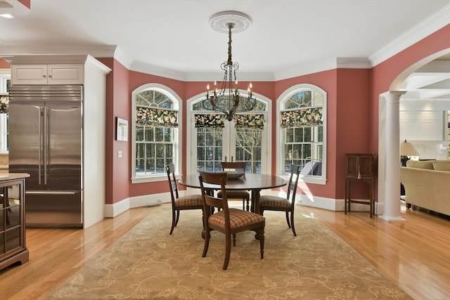 dining room featuring a healthy amount of sunlight, light wood-style floors, decorative columns, and arched walkways