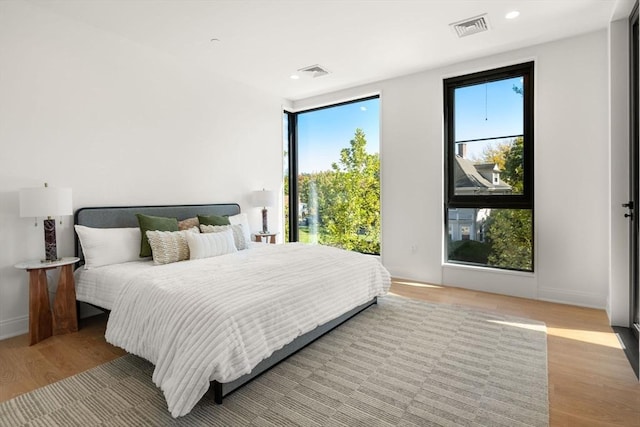 bedroom with multiple windows and light hardwood / wood-style flooring