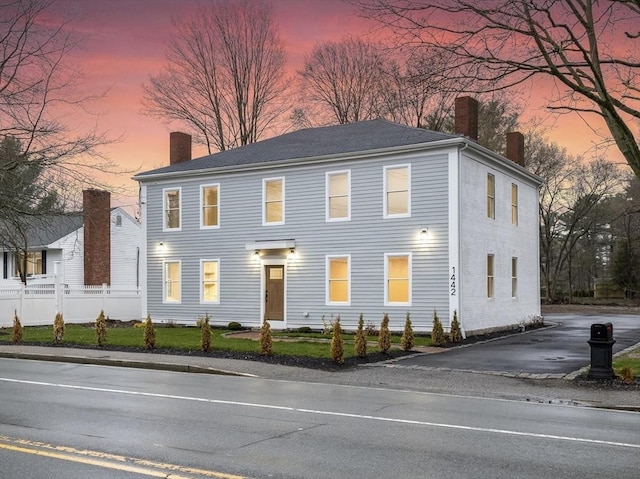 colonial inspired home with fence, driveway, and a chimney