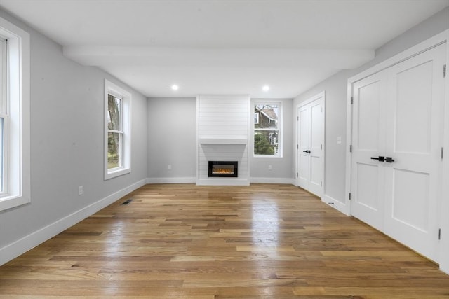 unfurnished living room with a large fireplace, baseboards, recessed lighting, visible vents, and light wood finished floors
