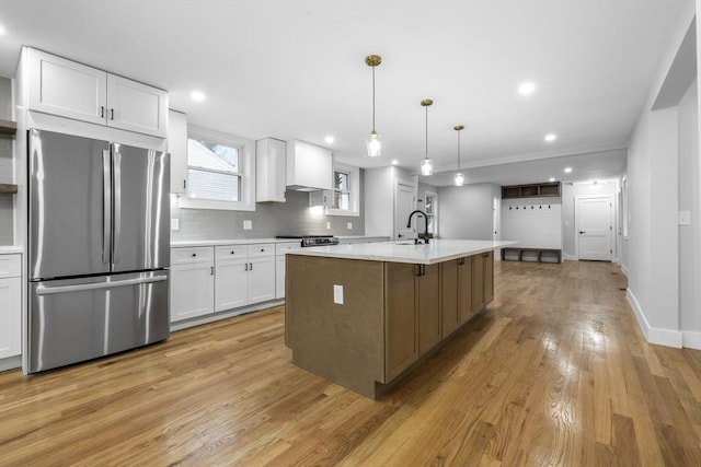 kitchen with white cabinets, light countertops, freestanding refrigerator, backsplash, and light wood-style flooring