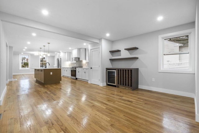 unfurnished living room featuring light wood-style flooring, a sink, baseboards, and recessed lighting