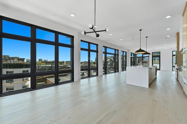 unfurnished living room featuring recessed lighting, a notable chandelier, plenty of natural light, and a sink