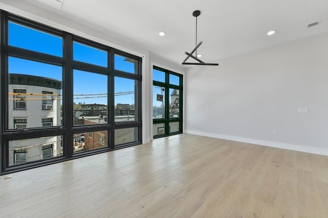 spare room featuring visible vents, recessed lighting, baseboards, and wood finished floors