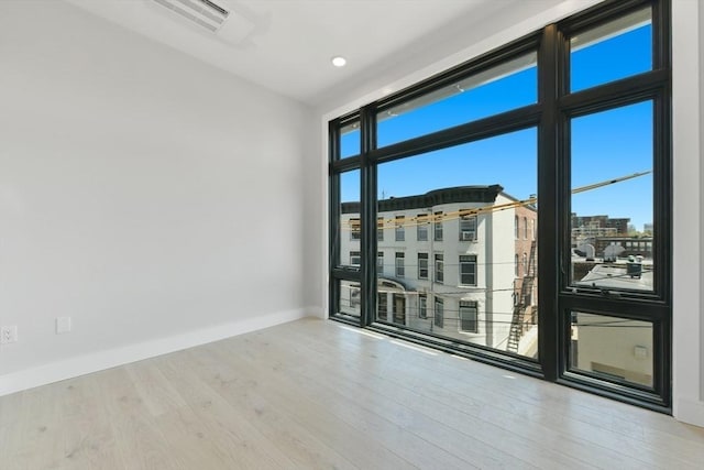 empty room featuring a healthy amount of sunlight, baseboards, and wood finished floors