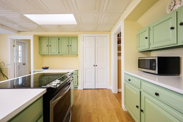 kitchen with an ornate ceiling, appliances with stainless steel finishes, light countertops, light wood-style floors, and green cabinets