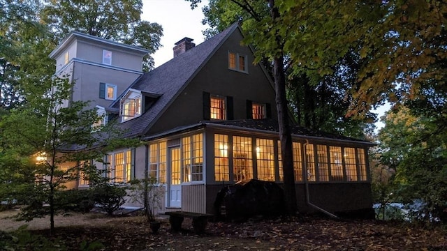 back of property with a chimney and stucco siding