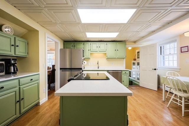 kitchen featuring green cabinets, stainless steel appliances, a sink, and an ornate ceiling