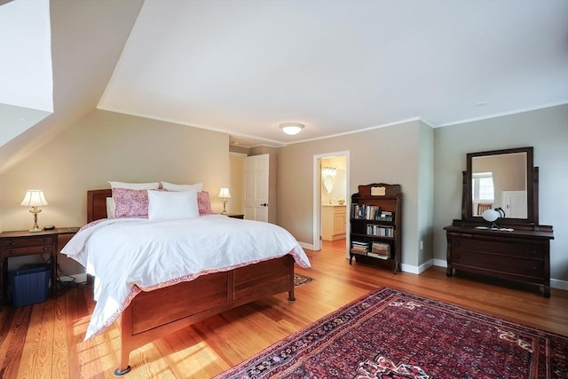 bedroom featuring ensuite bath, crown molding, baseboards, and wood finished floors