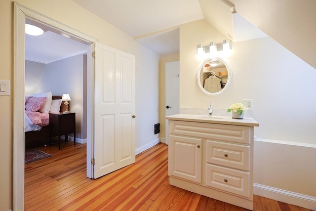 bathroom featuring ensuite bath, wood finished floors, vanity, and baseboards