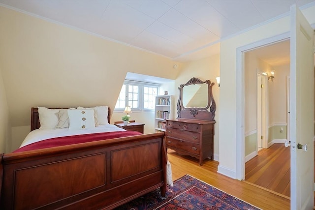 bedroom featuring light wood finished floors, baseboards, and crown molding