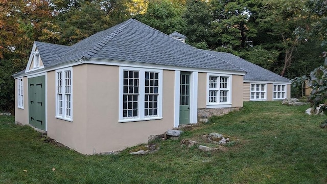 view of home's exterior featuring stucco siding, a lawn, and roof with shingles