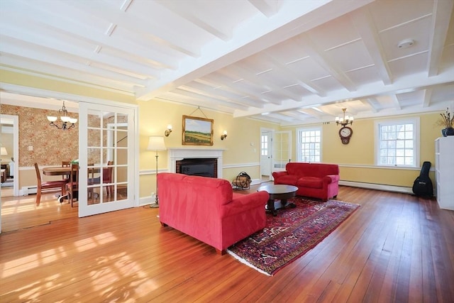 living area with a baseboard radiator, a notable chandelier, a fireplace, hardwood / wood-style floors, and beamed ceiling