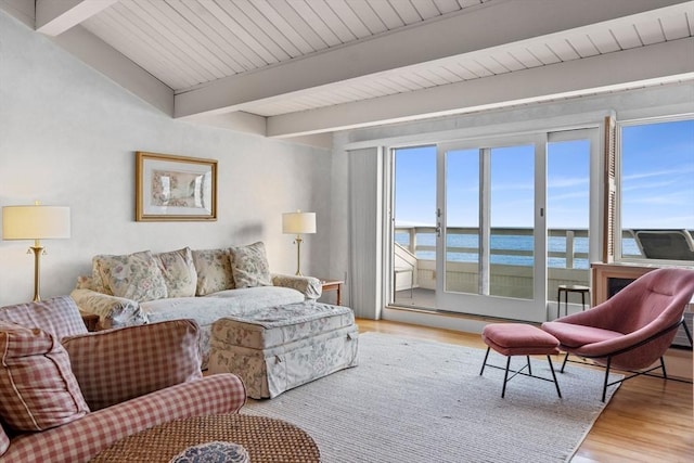 living room featuring beamed ceiling, a water view, a wealth of natural light, and light wood-type flooring