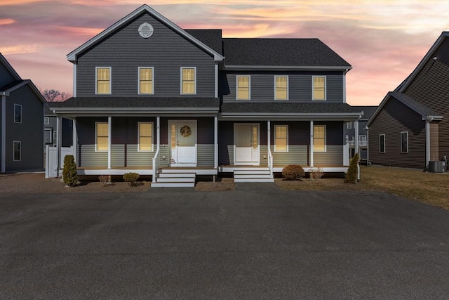 view of front of home featuring central AC unit, covered porch, and a shingled roof