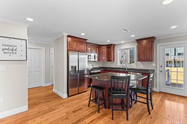 kitchen with visible vents, light wood-style flooring, appliances with stainless steel finishes, a breakfast bar area, and crown molding