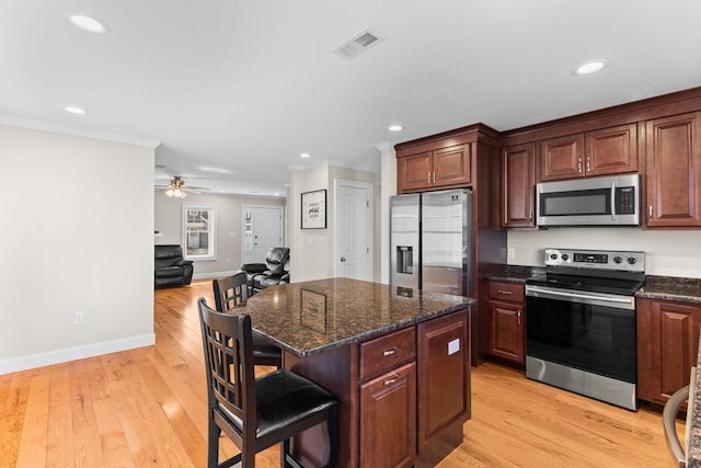 kitchen featuring visible vents, a kitchen bar, appliances with stainless steel finishes, and light wood-style flooring