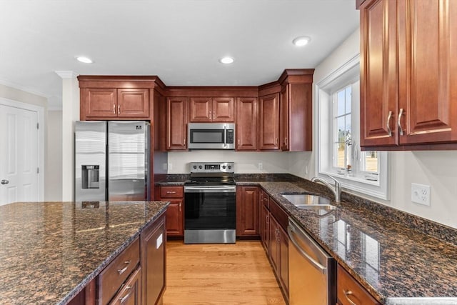 kitchen featuring light wood-style flooring, a sink, recessed lighting, stainless steel appliances, and dark stone counters