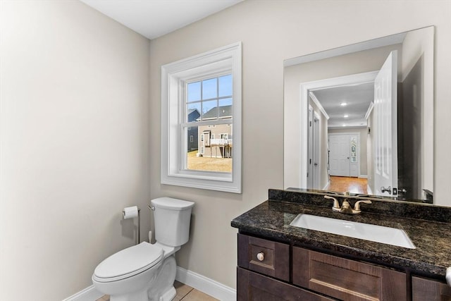 half bathroom with tile patterned floors, baseboards, toilet, and vanity