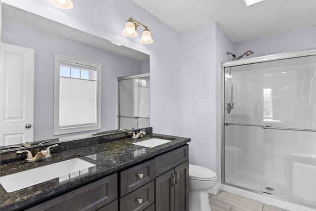 bathroom with double vanity, a shower stall, toilet, and a sink