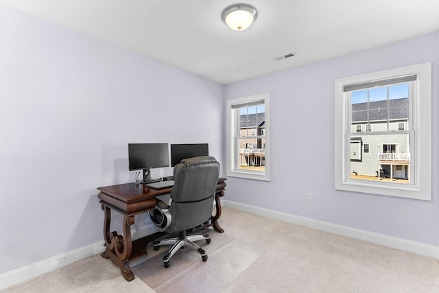 carpeted office featuring a wealth of natural light, visible vents, and baseboards