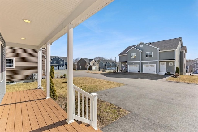 wooden terrace with an attached garage, a residential view, and driveway