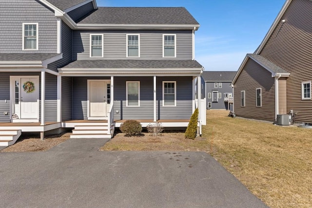 view of front of house with a porch, roof with shingles, central AC unit, and a front lawn