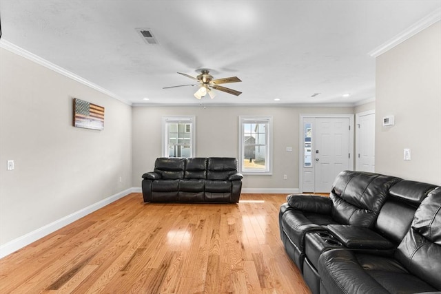 living area featuring visible vents, crown molding, baseboards, ceiling fan, and light wood-style flooring