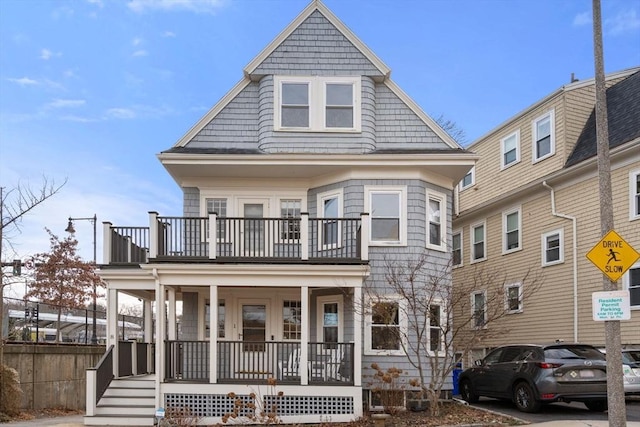 view of front of property featuring a balcony, covered porch, and fence