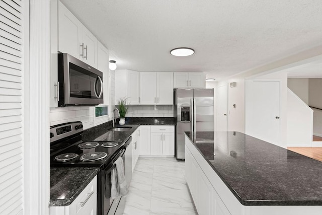 212 Fountain St Unit A, Framingham, MA 01702 - kitchen featuring stainless steel appliances, light marble finish flooring, a center island, tasteful backsplash, and white cabinetry