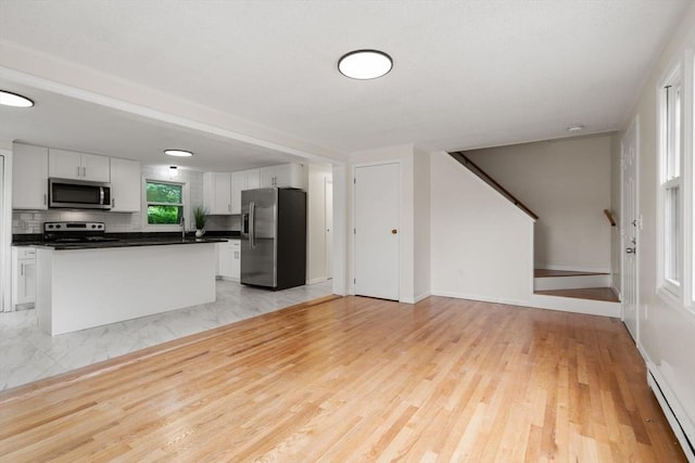 212 Fountain St Unit A, Framingham, MA 01702 - kitchen featuring stainless steel appliances, baseboard heating, white cabinets, open floor plan, and dark countertops