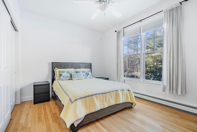 bedroom with wood-type flooring, a baseboard heating unit, and ceiling fan