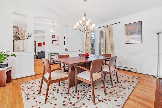 dining room with an inviting chandelier, ornamental molding, light hardwood / wood-style flooring, and a baseboard heating unit