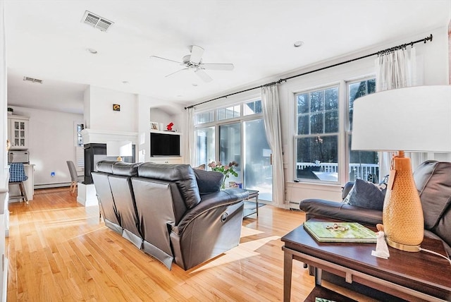 living room featuring ceiling fan, a baseboard radiator, and light wood-type flooring