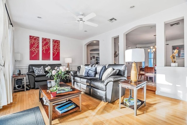 living room with ceiling fan with notable chandelier and hardwood / wood-style floors