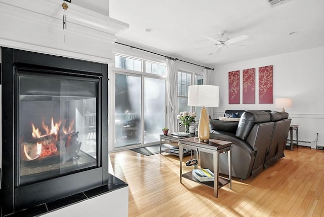 living room featuring light hardwood / wood-style flooring, ceiling fan, and baseboard heating