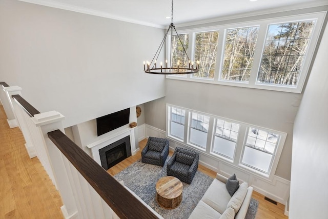 living room with hardwood / wood-style flooring, ornamental molding, and a notable chandelier