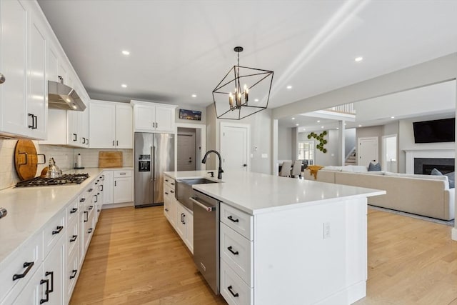 kitchen with pendant lighting, an island with sink, white cabinetry, decorative backsplash, and stainless steel appliances